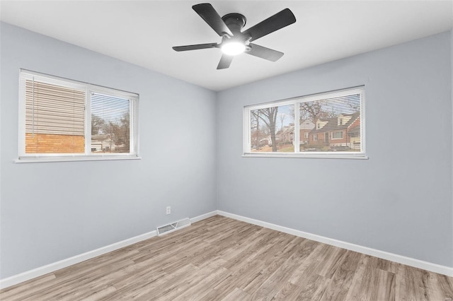 empty room with plenty of natural light, light hardwood / wood-style floors, and ceiling fan