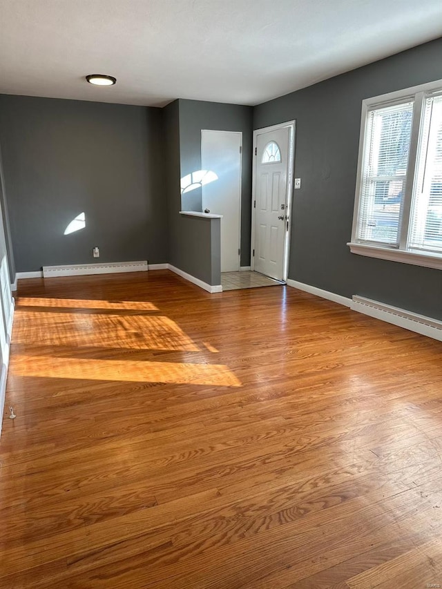 foyer entrance with baseboard heating and wood-type flooring