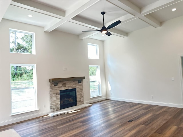 unfurnished living room with a fireplace, beam ceiling, dark wood-type flooring, and ceiling fan