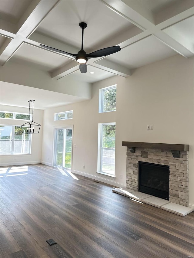 unfurnished living room featuring a fireplace, a healthy amount of sunlight, beam ceiling, and hardwood / wood-style floors