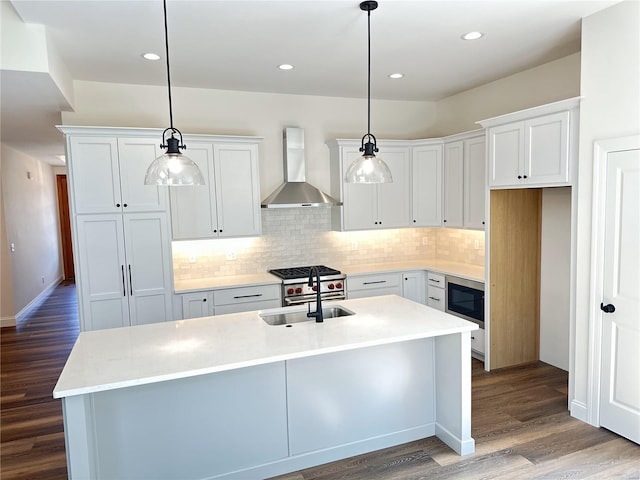 kitchen featuring white cabinetry, hanging light fixtures, sink, and wall chimney exhaust hood