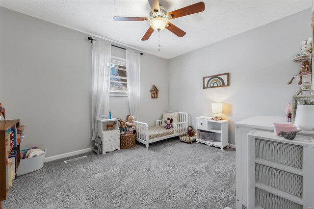 bedroom featuring a nursery area, ceiling fan, and carpet flooring