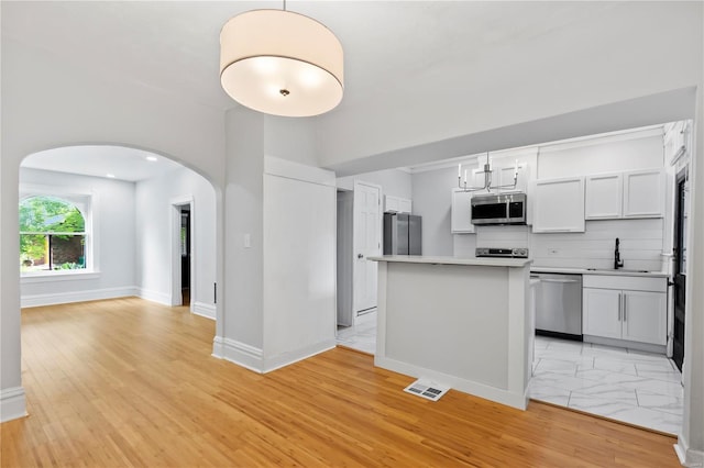 kitchen featuring sink, decorative light fixtures, stainless steel appliances, decorative backsplash, and white cabinets