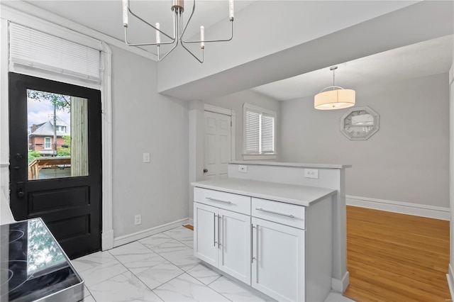 kitchen featuring white cabinetry, plenty of natural light, a chandelier, and pendant lighting