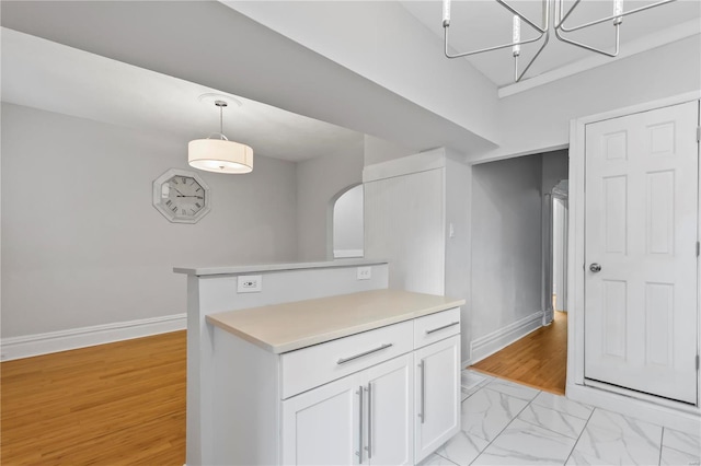 kitchen featuring white cabinetry, kitchen peninsula, and hanging light fixtures