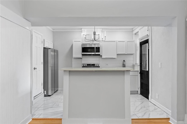 kitchen featuring pendant lighting, a kitchen island, white cabinets, and appliances with stainless steel finishes