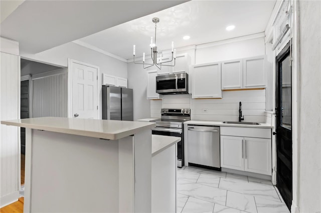 kitchen with pendant lighting, sink, appliances with stainless steel finishes, white cabinets, and a kitchen island