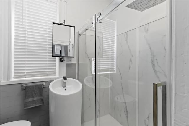 bathroom with a shower with door and tile walls