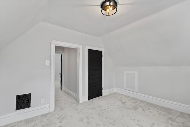 bonus room with lofted ceiling and light carpet