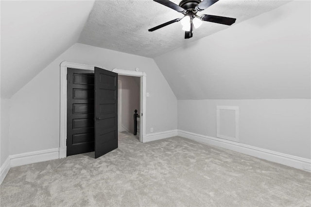 additional living space featuring light carpet, ceiling fan, vaulted ceiling, and a textured ceiling