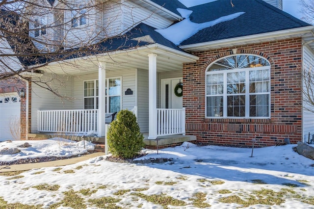 snow covered property entrance featuring a garage