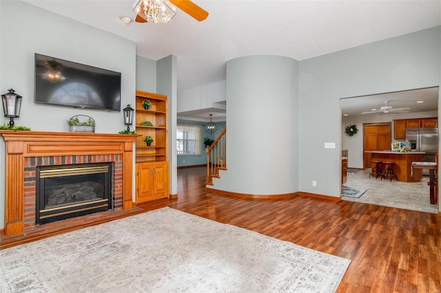 living room featuring hardwood / wood-style flooring, ceiling fan, and a fireplace