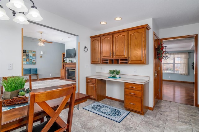 kitchen featuring hanging light fixtures, ceiling fan, and a fireplace