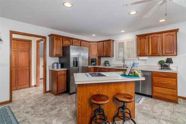 kitchen with sink, a breakfast bar area, a center island, appliances with stainless steel finishes, and ceiling fan