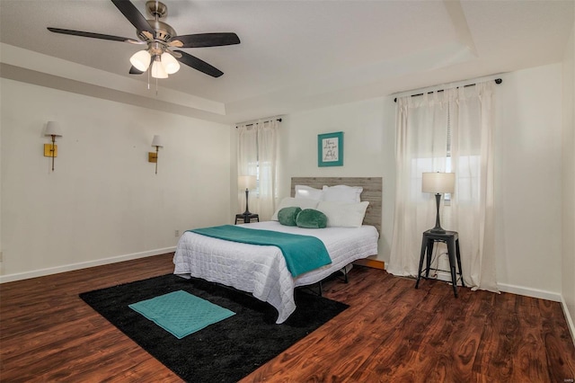 bedroom featuring a raised ceiling, ceiling fan, and dark hardwood / wood-style flooring