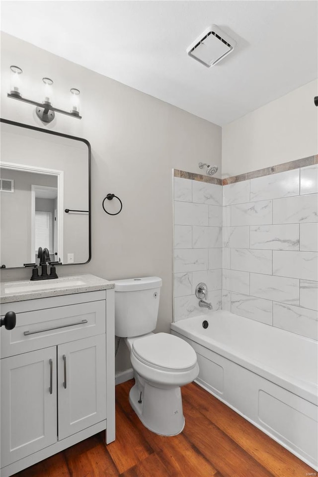 full bathroom with hardwood / wood-style flooring, vanity, toilet, and tiled shower / bath combo