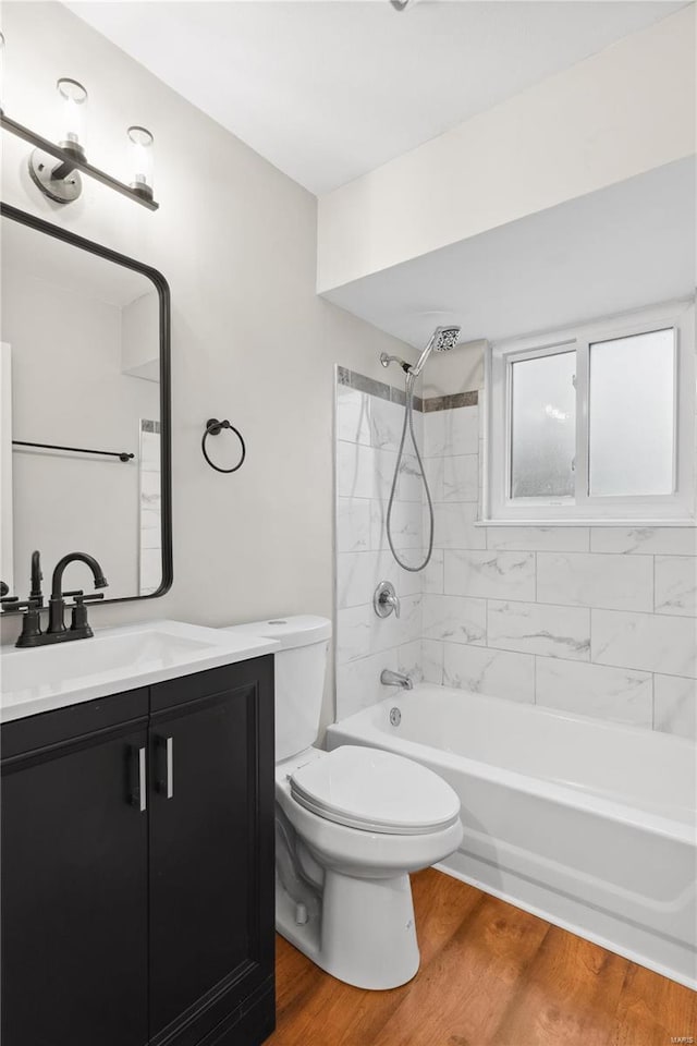 full bathroom featuring vanity, tiled shower / bath, hardwood / wood-style floors, and toilet