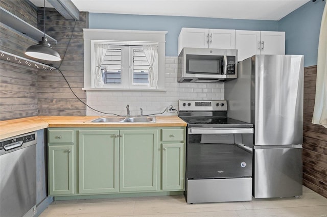 kitchen with stainless steel appliances, white cabinetry, butcher block counters, and decorative light fixtures