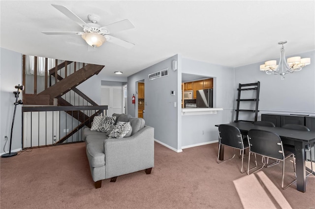 carpeted living room featuring ceiling fan with notable chandelier, stairway, visible vents, and baseboards