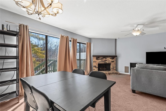dining room with baseboards, carpet, a textured ceiling, a brick fireplace, and ceiling fan with notable chandelier