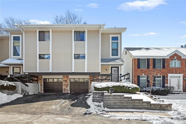 view of front facade with driveway, brick siding, and an attached garage