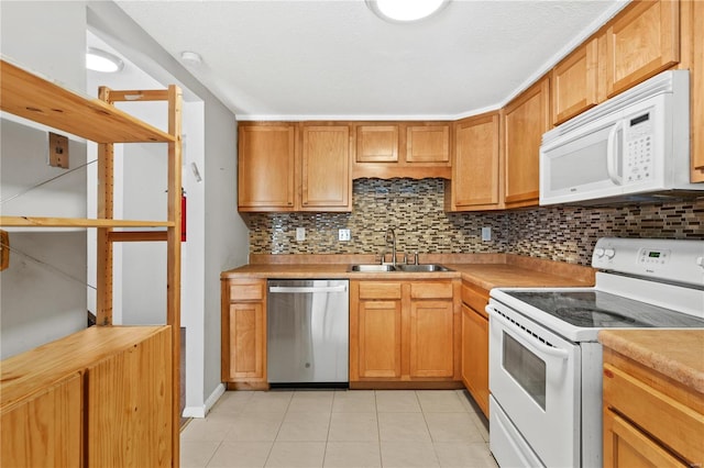 kitchen with light tile patterned flooring, white appliances, a sink, light countertops, and decorative backsplash