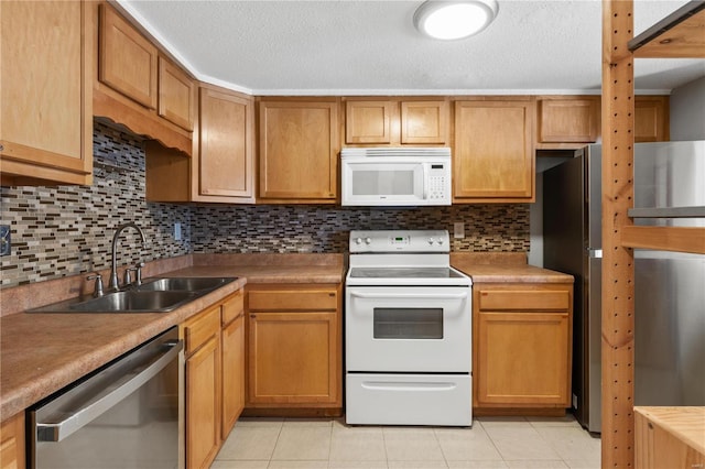 kitchen featuring light tile patterned floors, white appliances, backsplash, and a sink