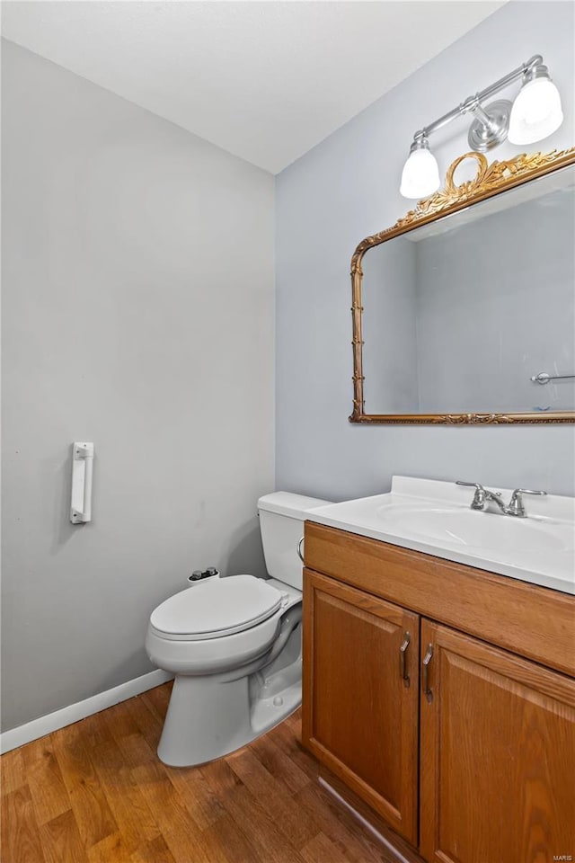 bathroom with baseboards, vanity, toilet, and wood finished floors