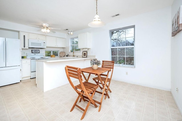 kitchen with pendant lighting, tasteful backsplash, white cabinets, ceiling fan, and white appliances