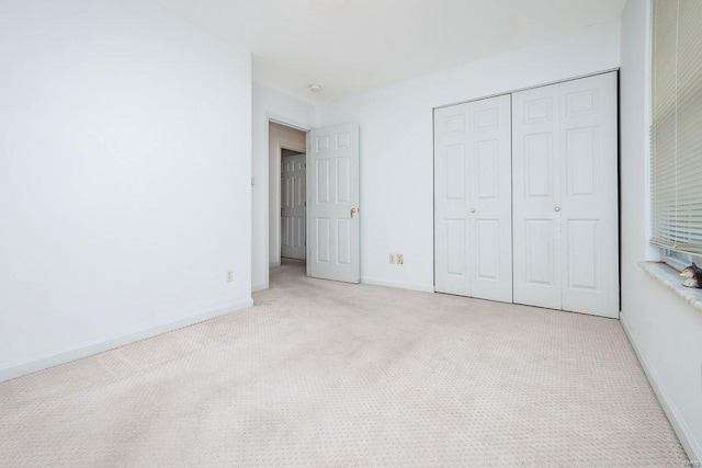 unfurnished bedroom with light carpet and a closet