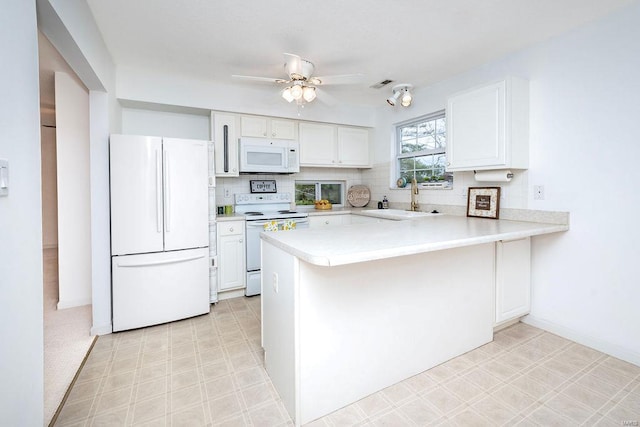 kitchen featuring sink, white appliances, kitchen peninsula, and white cabinets