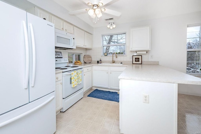 kitchen with white cabinetry, white appliances, a wealth of natural light, and kitchen peninsula