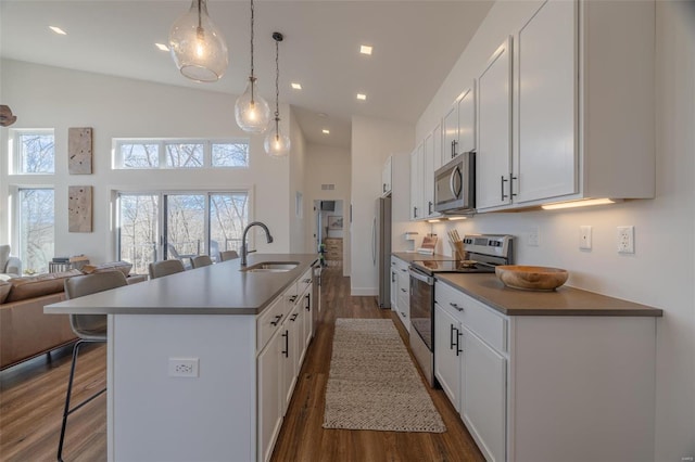 kitchen featuring sink, a breakfast bar area, white cabinetry, a center island with sink, and appliances with stainless steel finishes