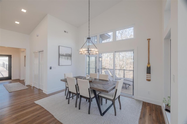 dining room with an inviting chandelier, wood-type flooring, and a high ceiling