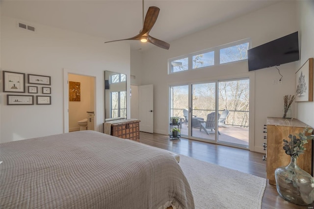 bedroom featuring ceiling fan, access to exterior, dark hardwood / wood-style flooring, and a high ceiling