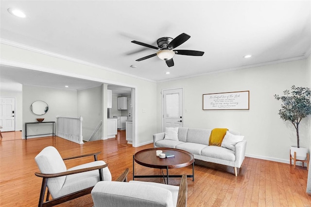 living room featuring crown molding, ceiling fan, washer and clothes dryer, and light hardwood / wood-style floors