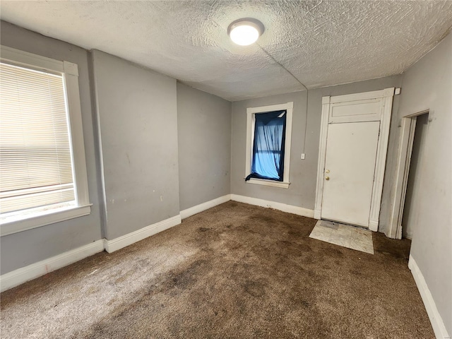 empty room with dark carpet and a textured ceiling