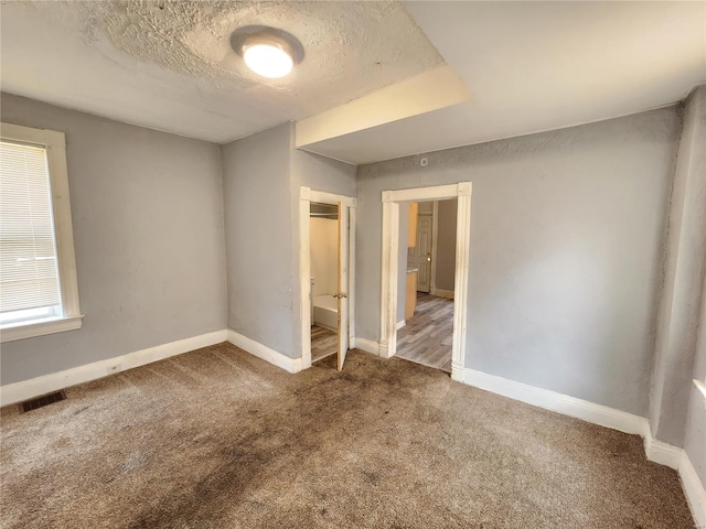 unfurnished room with dark carpet and a textured ceiling