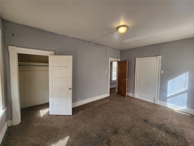 unfurnished bedroom with a closet and dark colored carpet