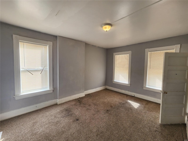 empty room featuring a wealth of natural light and dark carpet