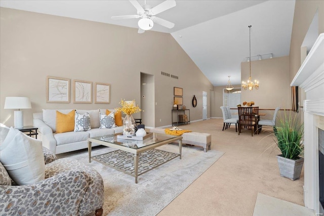 carpeted living room with ceiling fan with notable chandelier, a high end fireplace, and high vaulted ceiling