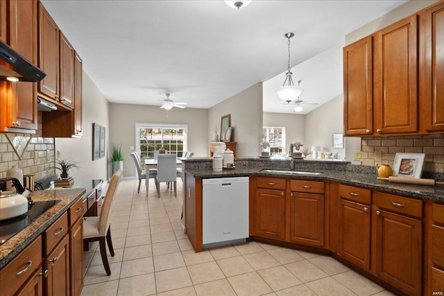 kitchen with pendant lighting, sink, white dishwasher, decorative backsplash, and kitchen peninsula