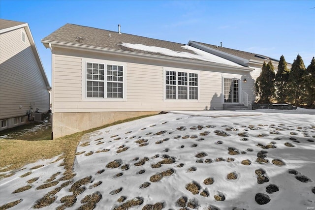 snow covered back of property with central air condition unit