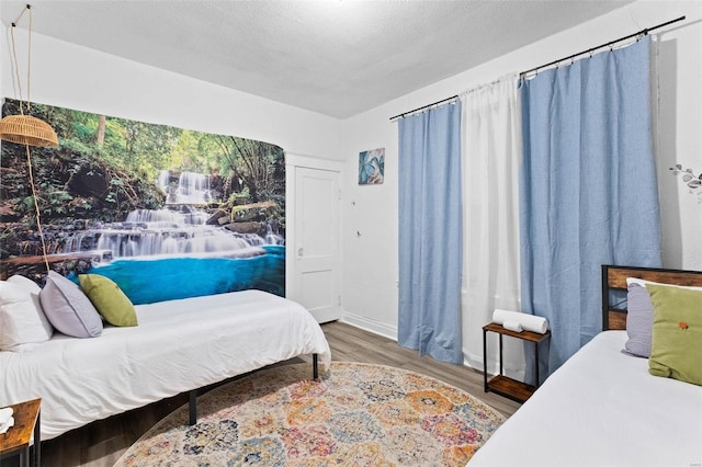 bedroom with a textured ceiling and wood finished floors