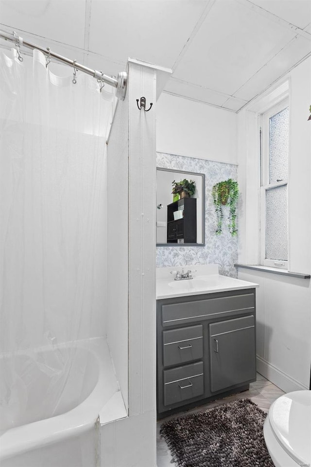 full bath with shower / bathtub combination with curtain, toilet, vanity, baseboards, and wallpapered walls