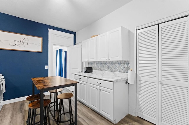 kitchen featuring light stone counters, tasteful backsplash, white cabinetry, and light wood-style floors