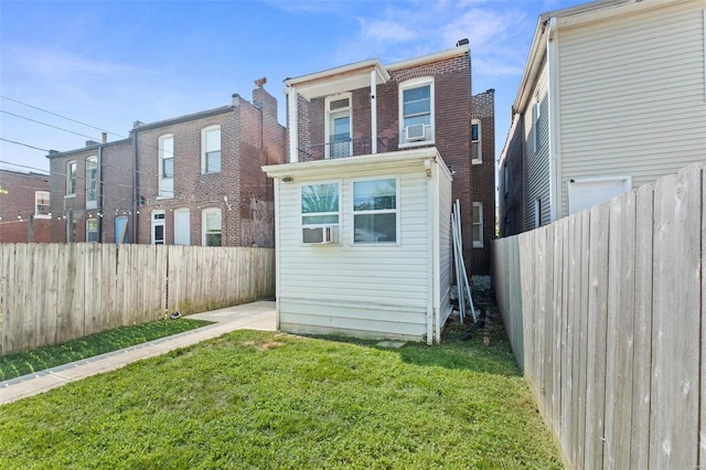 rear view of property with a yard, brick siding, cooling unit, and a fenced backyard