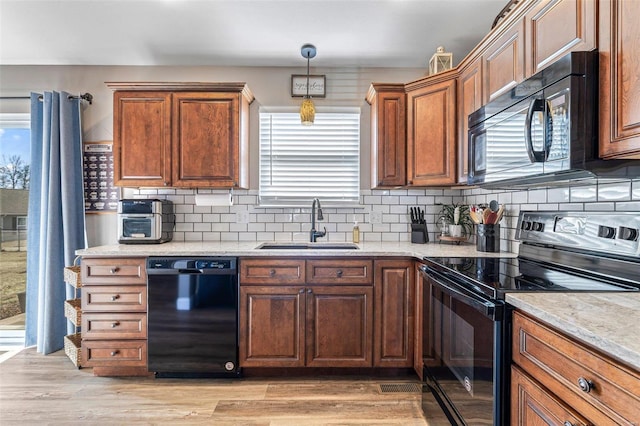 kitchen with sink, light stone counters, black appliances, light hardwood / wood-style floors, and backsplash