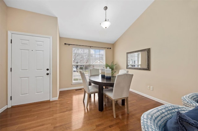 dining room featuring lofted ceiling, wood finished floors, and baseboards