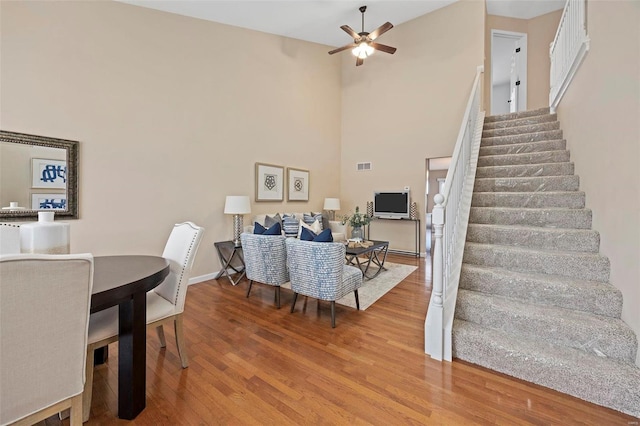 interior space featuring visible vents, a high ceiling, ceiling fan, wood finished floors, and stairs